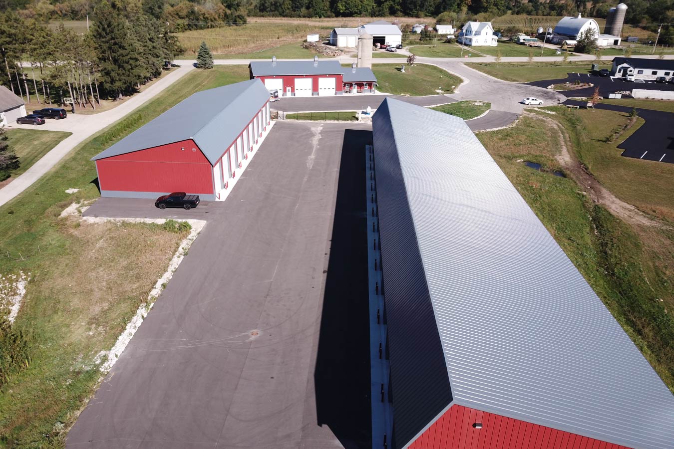 Aerial view of Lone Silo Storage facilities in Waukesha Wisconsin with multiple red post frame storage buildings and gray metal roofs. Roof