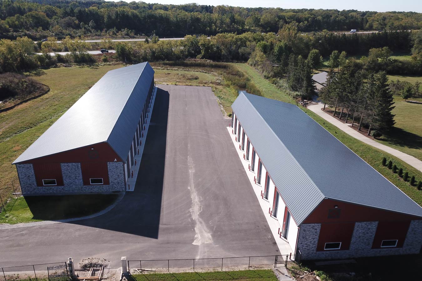 Aerial view of Lone Silo Storage facilities in Waukesha Wisconsin with two large red post frame storage buildings and gray metal roofs.