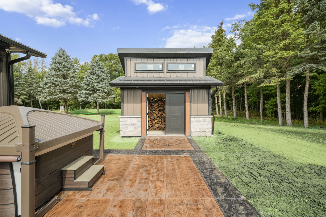 Small storage shed matching a custom monitor barndominium with vertical steel siding and stone wainscot