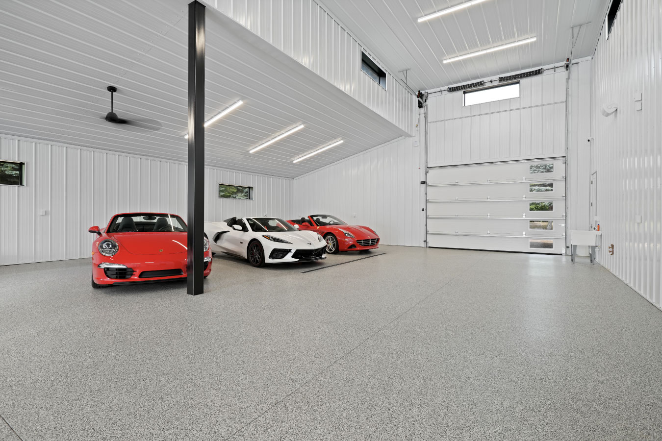 Luxury car garage inside a custom monitor barndominium with high ceilings and white steel liner panels