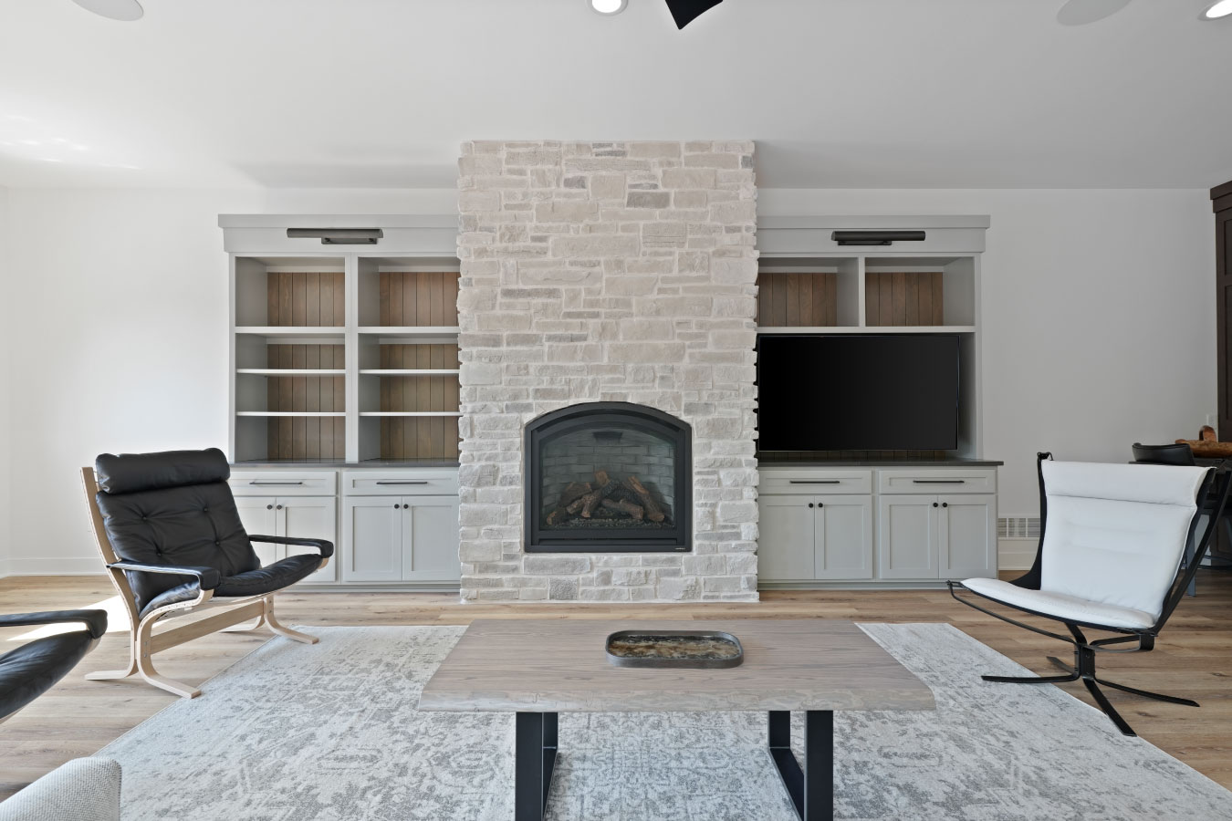 Living room inside a custom monitor barndominium with stone fireplace and built-in cabinetry