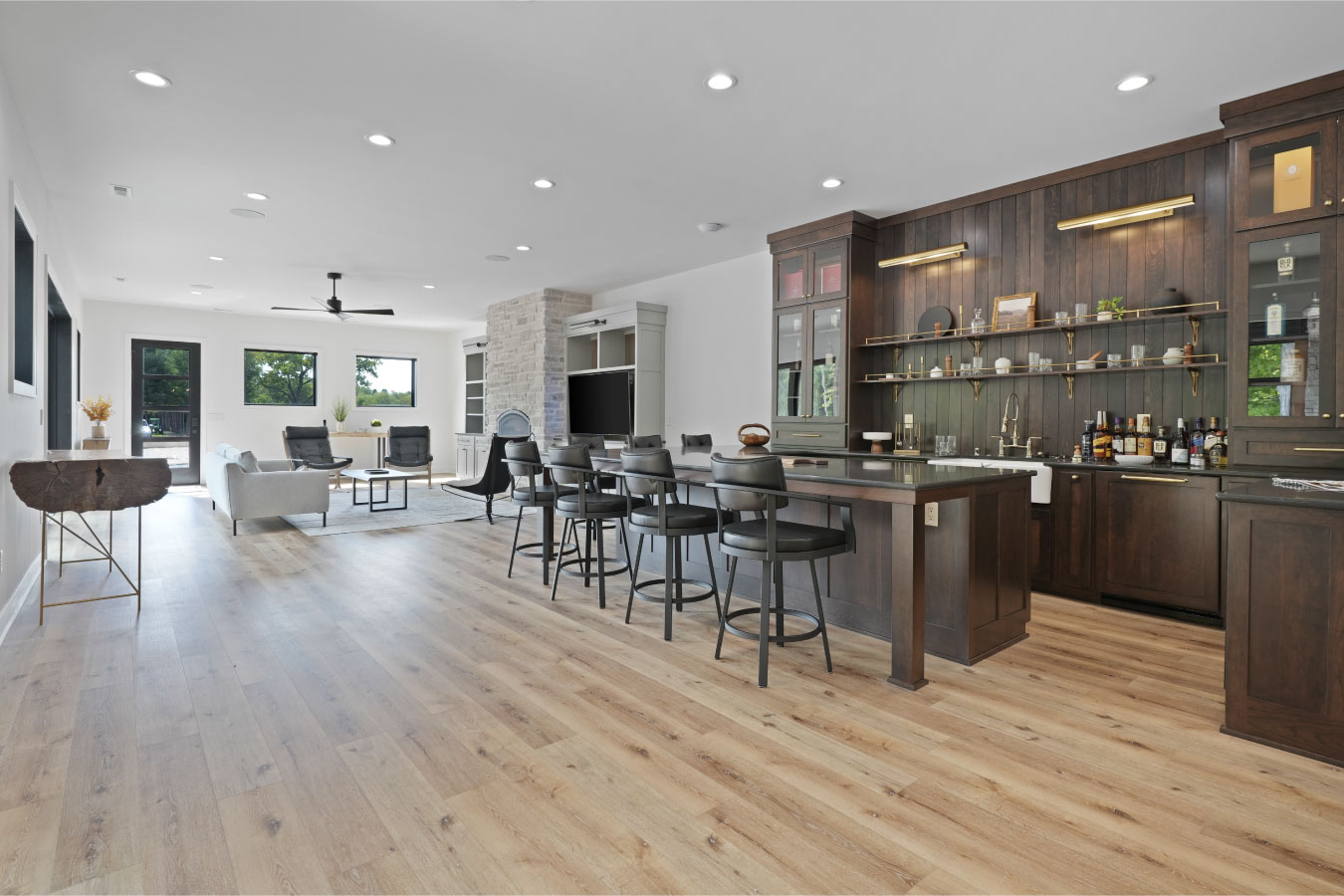 Open concept kitchen and bar inside a luxury monitor barndominium with hardwood floors and custom cabinetry
