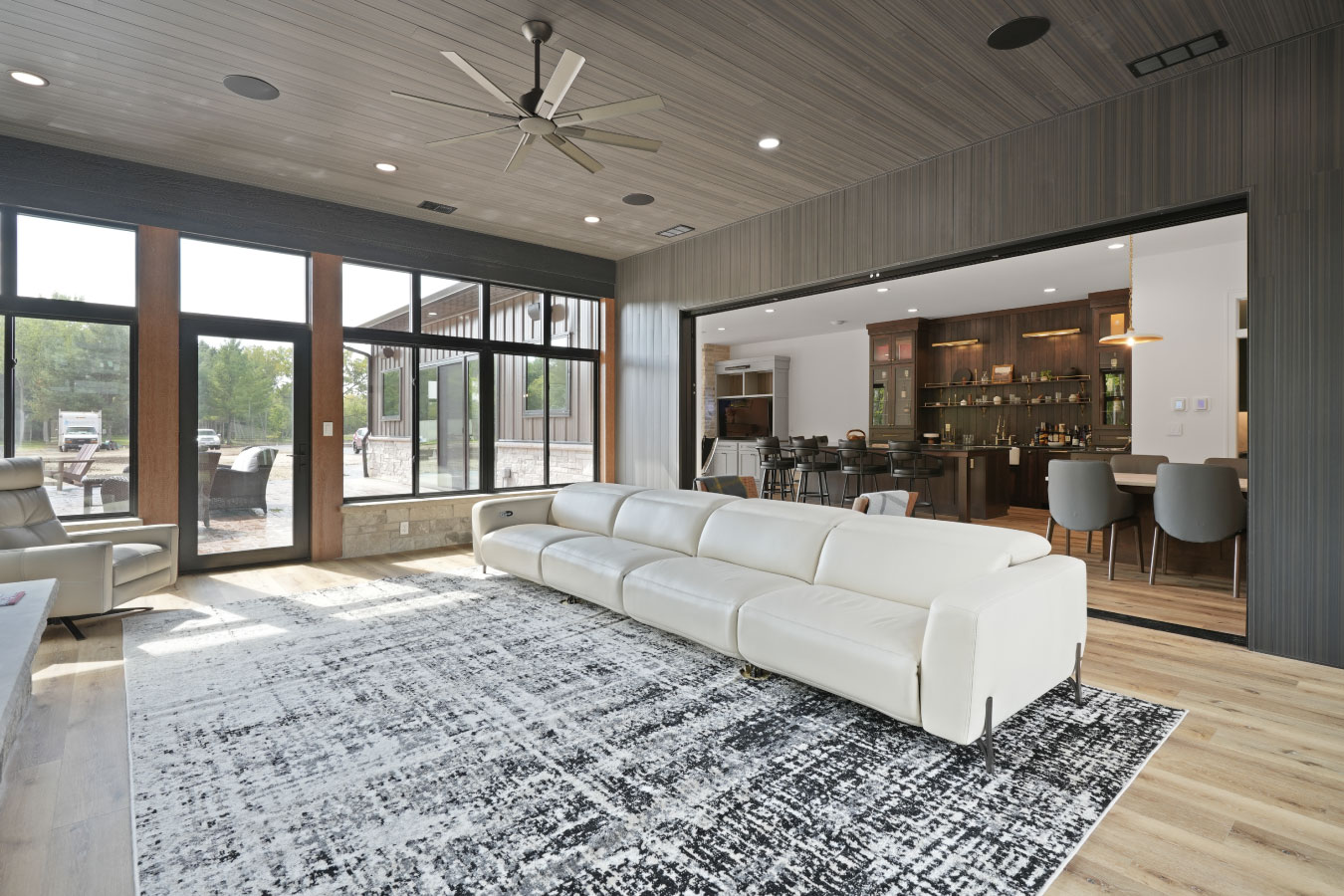 Four-season room inside a custom monitor barndominium with large windows and open view to kitchen and bar area