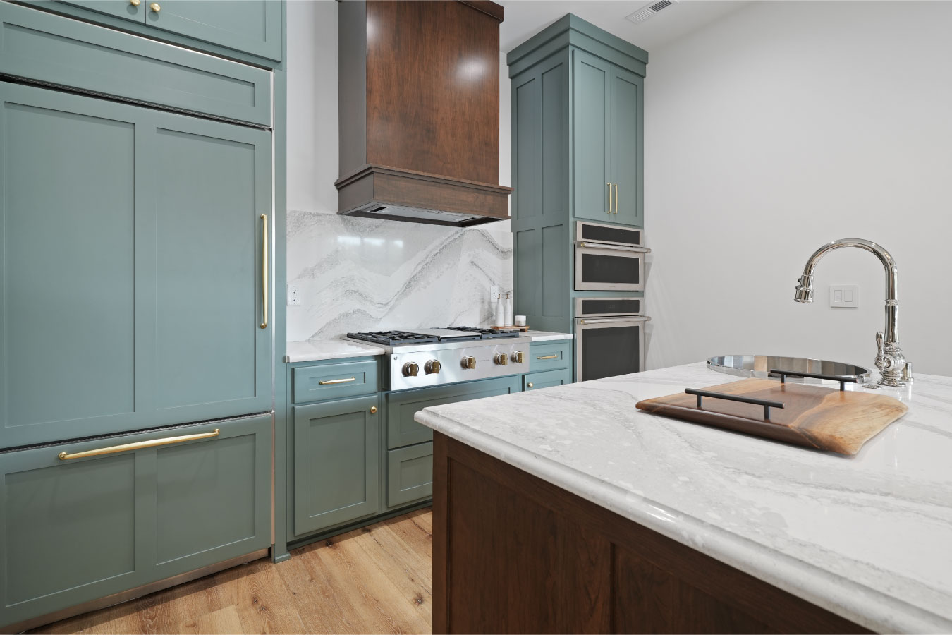 Custom kitchen inside a luxury monitor barndominium with green cabinetry, marble countertops, and built-in appliances