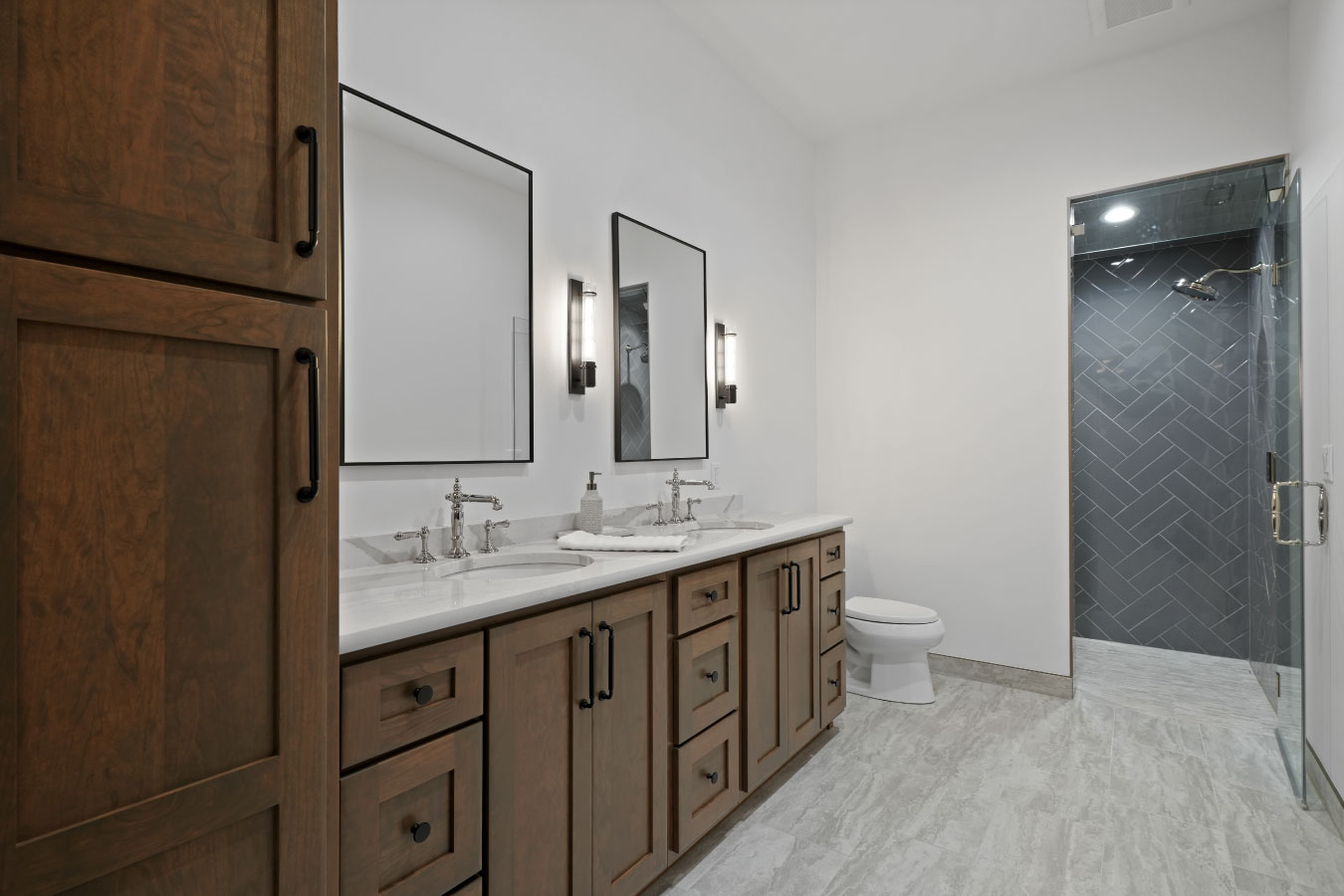 Primary bathroom inside a custom monitor barndominium with double vanity and walk-in tile shower