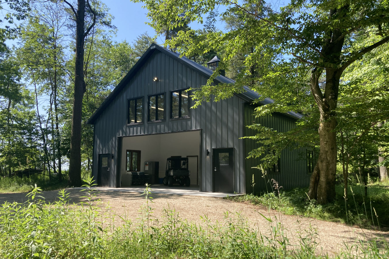 Shop with living quarters with steel siding, open garage bay, and upper-level windows
