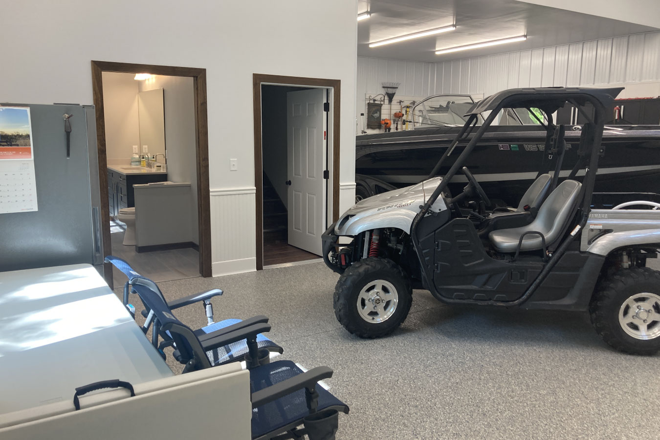 Shop with living quarters interior showing garage space with side-by-side vehicle and connected bathroom
