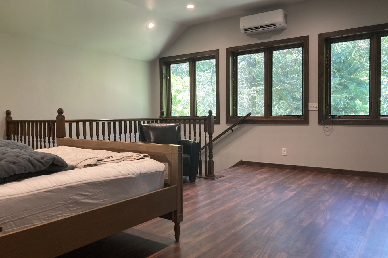 Shop with living quarters bedroom featuring multiple windows, wood flooring, and natural light