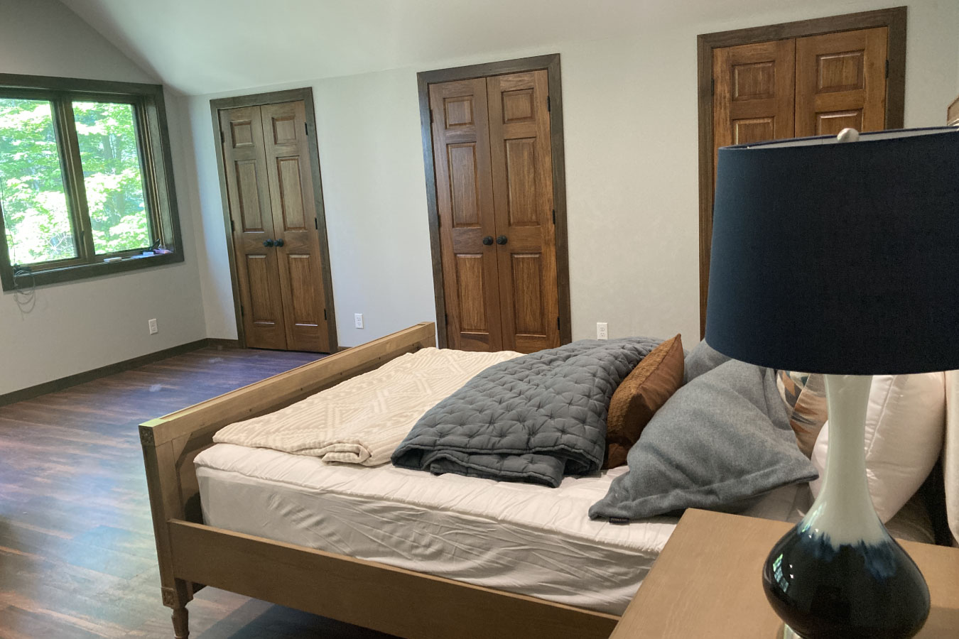 Shop with living quarters bedroom with wood flooring, windows, and double closet doors
