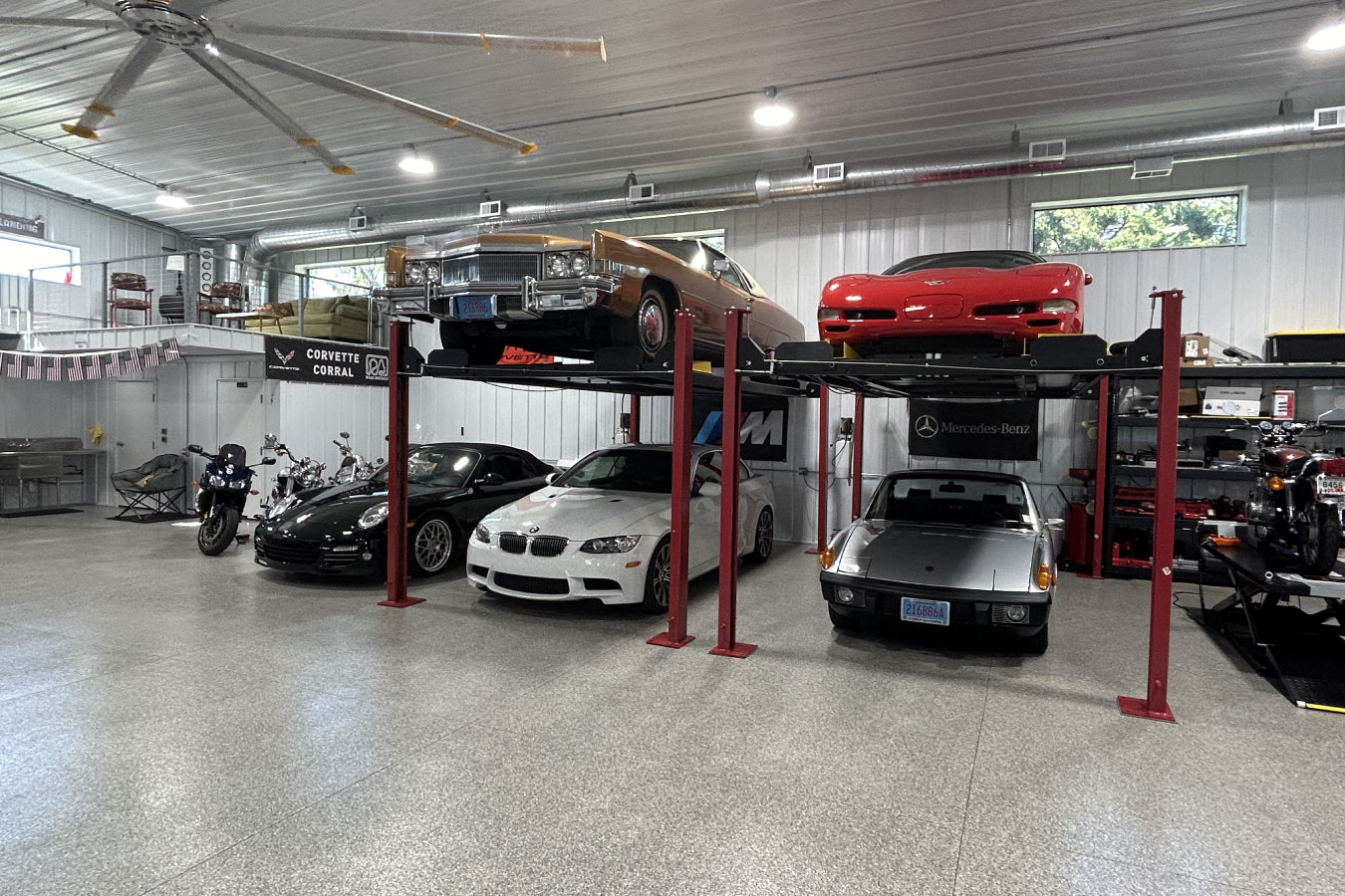 This man cave garage interior is designed for car enthusiasts, featuring multiple vehicle lifts that maximize storage and display space. With high ceilings, bright overhead lighting, and a clean, open layout, the space functions as both a working garage and a showcase for classic and performance vehicles, making it the ultimate automotive man cave.
