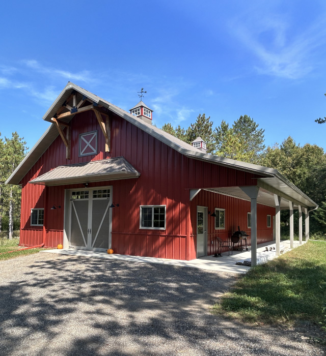 Pole barn workshop with overhead door, covered porch, cupolas, and workshop entry