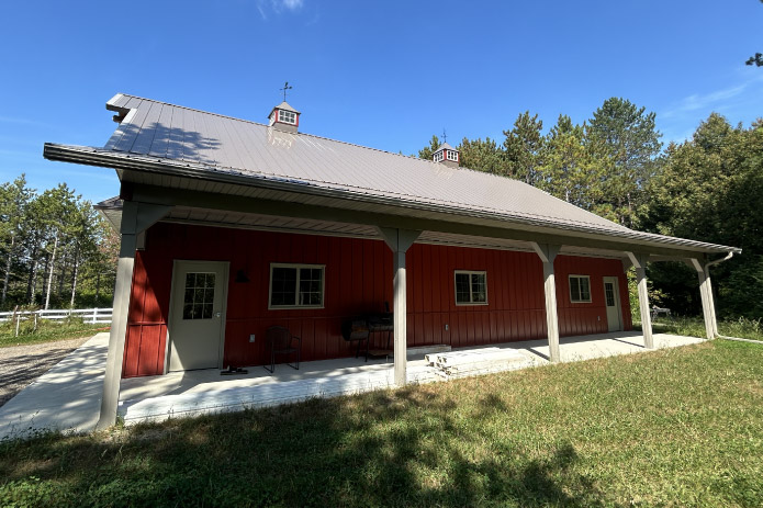 Pole barn workshop with full-length covered porch, support posts, and walk doors