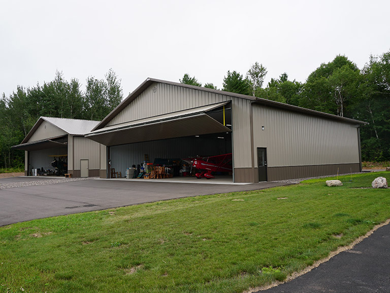 Post-Frame Storage Building with Large Overhead Door for Equipment or Aircraft Post-frame storage building with large overhead door, steel siding, and aircraft storage use
