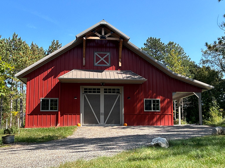 Post-Frame Storage Building with Sliding Doors and Covered Overhang Post-frame storage building with red steel siding, sliding barn doors, covered overhang, and residential-style design
