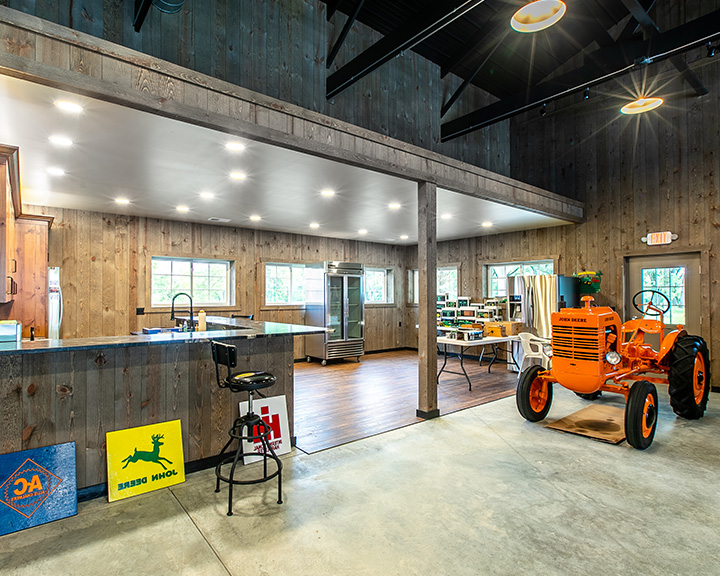 Post-frame hobby workshop interior with loft, wood walls, open workspace, bar area, and equipment storage