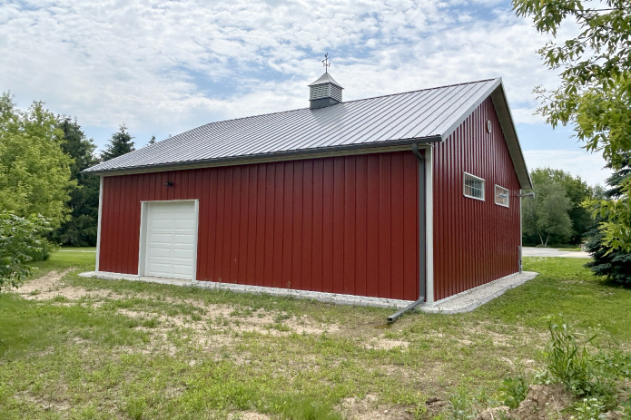36x40 garage with red steel siding, white overhead door, and metal roof