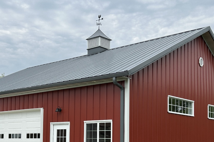36x40 garage featuring red steel siding, white overhead door, and a classic cupola.