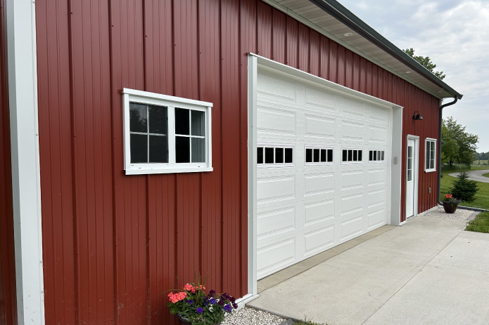 36x40 garage with red steel siding, white overhead door with windows, and walk door