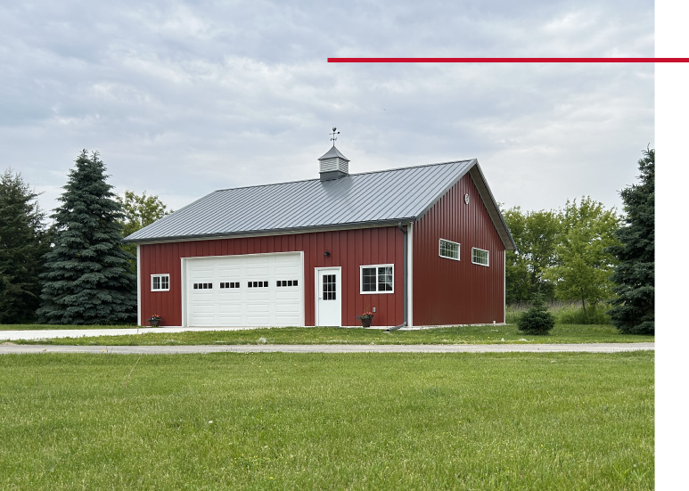 36x40 garage with red steel siding, white overhead door, and cupola in rural setting