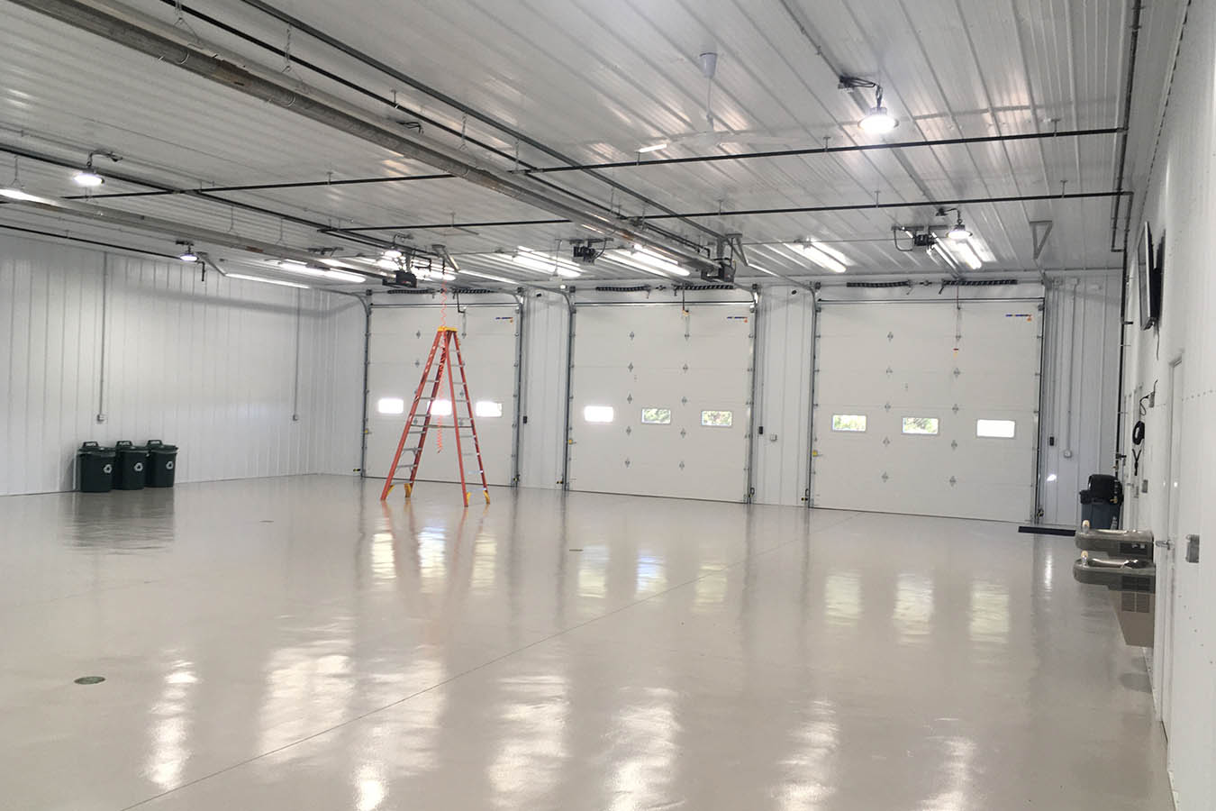 Interior fire department apparatus bay with three overhead doors Drive-Thru Doors Synced to Open on Both Sides