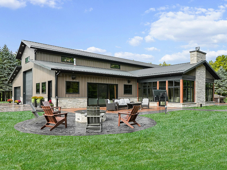 Luxury Barndominium with Outdoor Living Space and Fire Pit Luxury barndominium with steel siding, covered patio, outdoor fire pit, and modern residential design on landscaped property