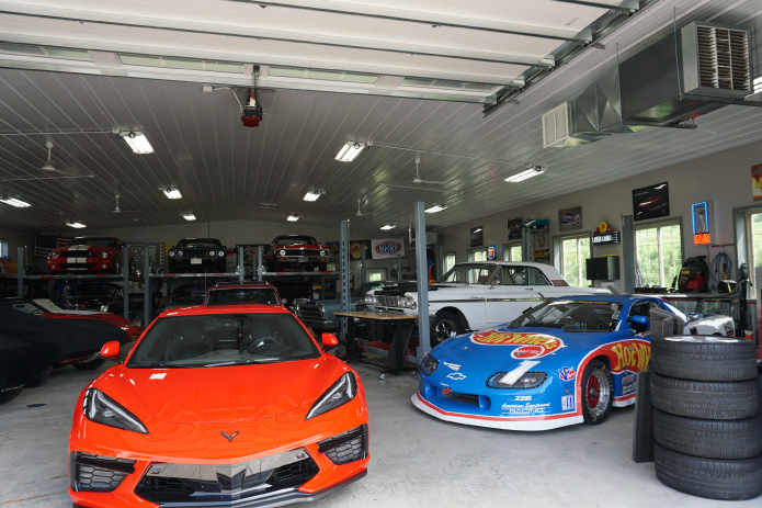 Car Collection Garage Interior with Vehicle Lifts and Open Layout | Post Frame Building | Walters Buildings This car collection garage interior is designed to showcase a diverse range of vehicles, from race cars to classic models, all within a highly functional post frame construction space. The open layout allows for seamless organization and display, giving each vehicle room to stand out while maintaining accessibility. The inclusion of vehicle lifts maximizes storage capacity by utilizing vertical space, while the high ceilings—made possible by post frame construction—accommodate multiple levels of vehicle storage with ease. The polished concrete floor provides durability and easy maintenance, ideal for both storage and active use. Natural light enters through a row of upper wall windows, complemented by bright overhead lighting that ensures the entire space remains well-lit. The interior also features areas for tools, collectibles, and automotive memorabilia, creating a true enthusiast’s showroom environment. This car collection garage highlights how post frame construction can deliver a premium, high-performance space tailored for serious collectors who value both function and presentation.