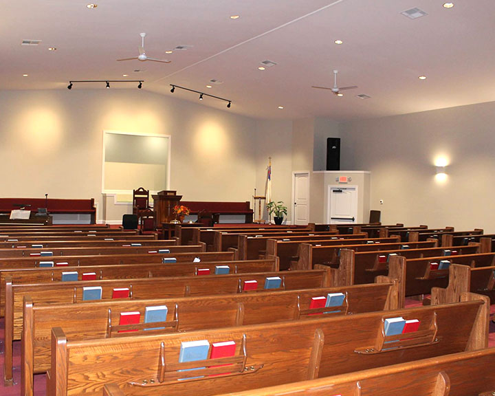 Church sanctuary interior with pew seating, stage, and clear-span worship space
