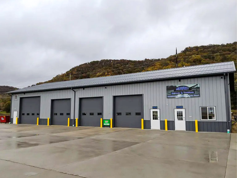 Auto Repair Shop with Multiple Service Bays and Customer Entry | Walters Buildings Auto repair shop building with steel siding, multiple overhead doors, and customer entrance