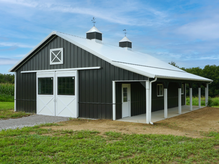 Custom Horse Barn with Cupolas, Sliding Doors, and Covered Porch Custom post-frame horse barn with steel siding, cupolas, sliding doors, and covered porch