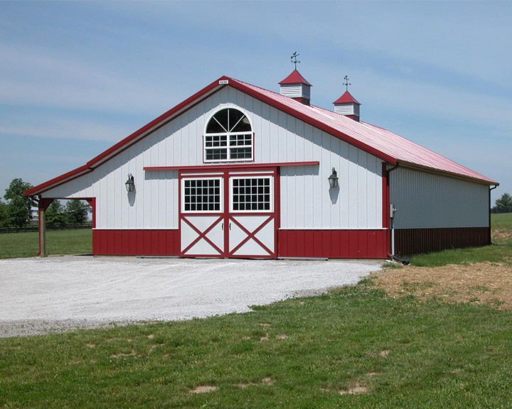 Premium equestrian barn featuring covered porch, stone exterior, and ventilation designed for comfort and daily care