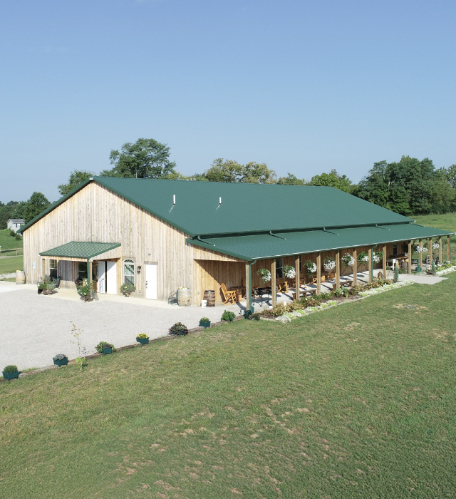 Rustic barn wedding venue with green metal roof, wood siding, and covered porch for ceremonies and receptions Finchville, Kentucky