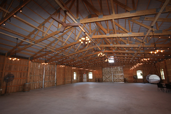 Large rustic barn wedding venue interior with exposed timber trusses and string lighting