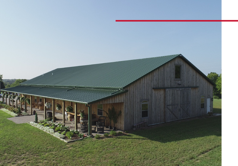 Rustic barn wedding venue with green metal roof and covered wraparound porch