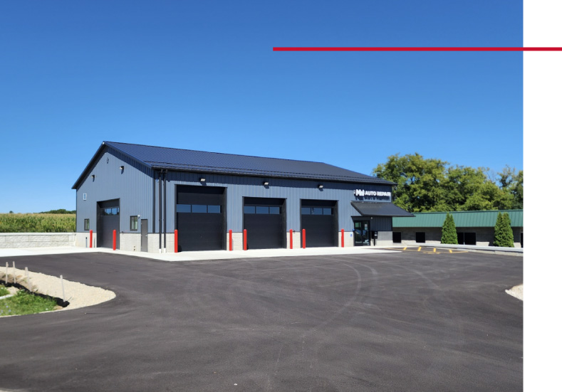 Post-Frame Auto Repair Shop Building – MW Auto Repair post-frame auto repair shop building with multiple overhead garage doors and large parking area