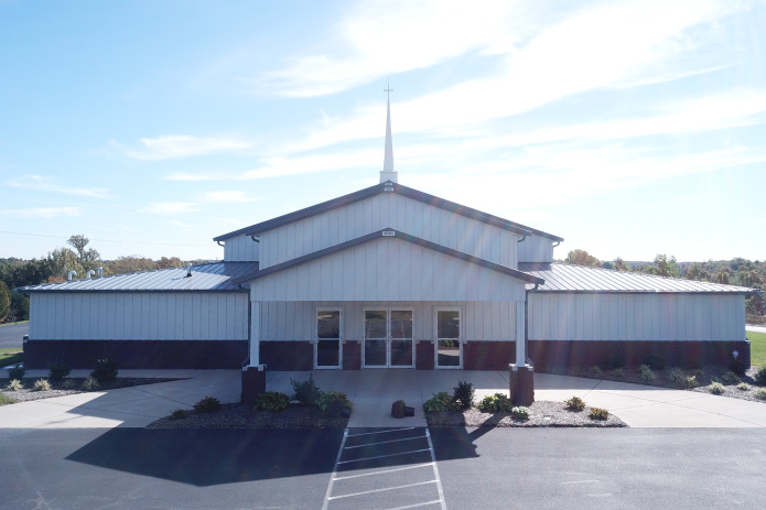 Pleasant Hill Christian Church Entrance | Post Frame Church Building Front entrance of Pleasant Hill Christian Church featuring white metal siding, gray steel roof, brick wainscot, and church steeple.