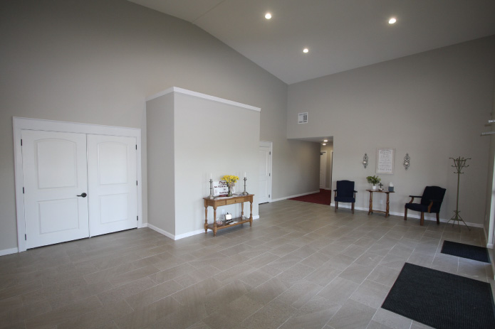 Church Lobby Interior with Vaulted Ceiling and Tile Flooring Church lobby interior with high vaulted ceiling, tile flooring, white double doors, and entry seating area
