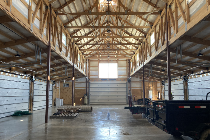 Interior of monitor barn agricultural storage building with engineered trusses, clerestory windows, and open equipment space