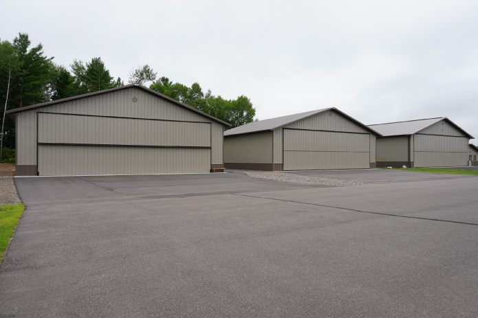 Airport Hangar Buildings with Large Aircraft Doors | Walters Buildings airport hangar buildings with large aircraft doors and paved runway access in wooded setting