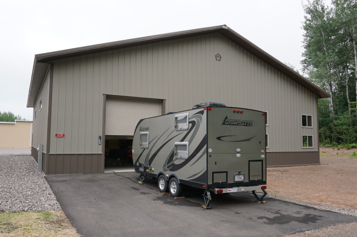 Airport Hangar with Overhead Door Access | Walters Buildings airport hangar with overhead door and trailer parked outside on paved driveway