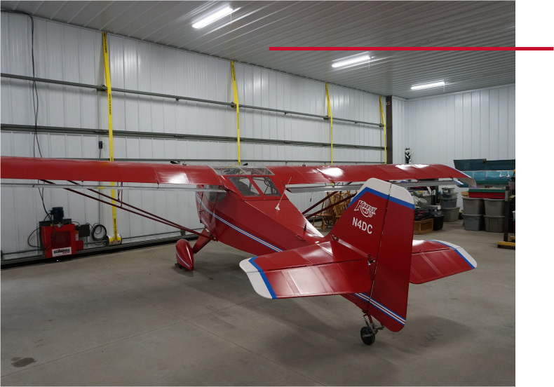 Airport Hangar Interior with Aircraft and Steel Walls | Walters Buildings airport hangar interior with red airplane and steel wall panels and overhead lighting