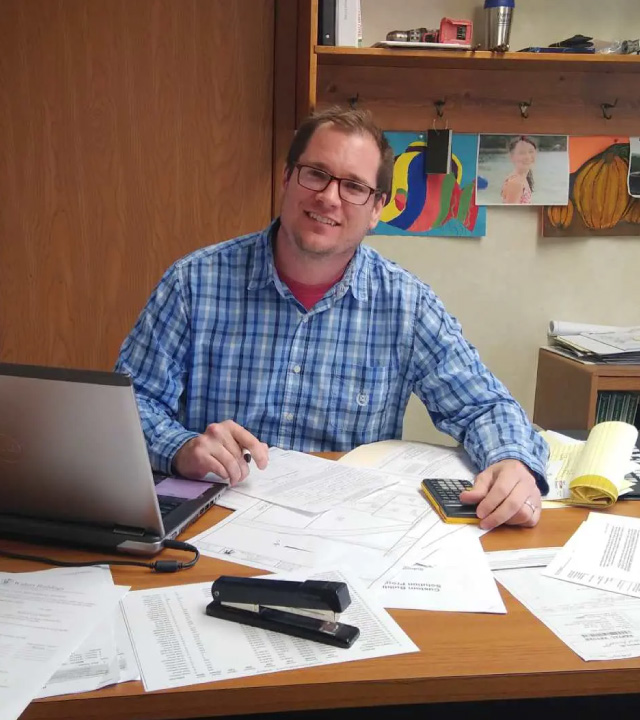 Walters Buildings Representative Providing Personalized Project Planning Walters Buildings representative working with plans and estimates at desk providing personalized building consultation