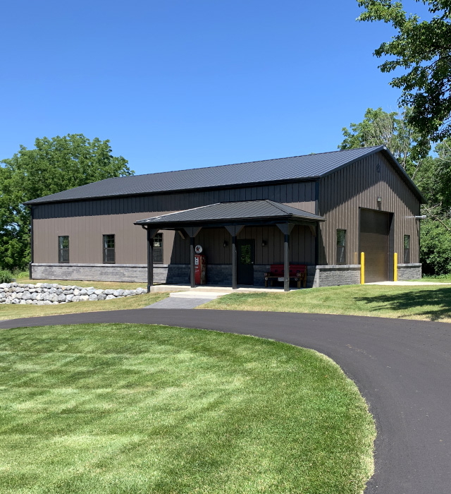 Pole Barn Garage with Stone Wainscot and Covered Porch | Walters Buildings pole barn garage with bronze steel siding black trim stone wainscot and covered porch in Wisconsin