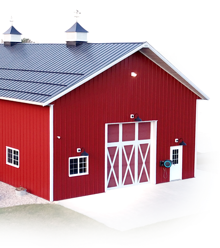 Red steel post-frame barn with overhead door, cupolas, and wainscot exterior
