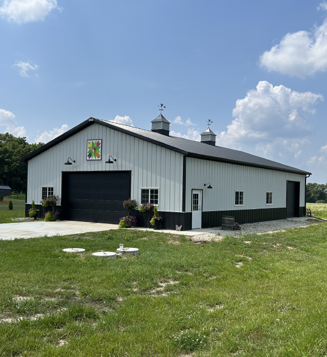 42x64 pole barn garage with white steel siding, black wainscot, and dual cupolas Rural Pole Barn Garage in Waterford, Wisconsin