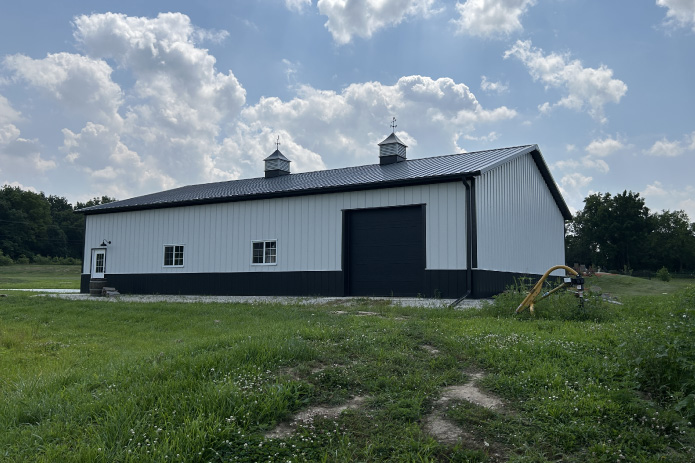 42x64 pole barn garage with white steel siding, black wainscot, and large overhead door