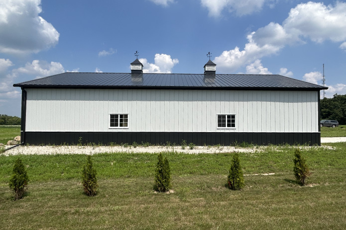 42x64 pole barn garage with white steel siding, black wainscot, and rear windows