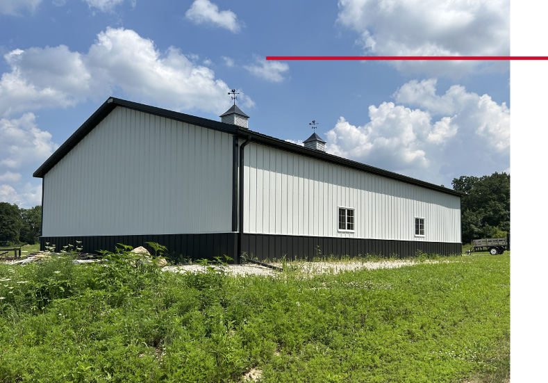 42x64 pole barn garage side view with white steel siding, black wainscot, and cupolas