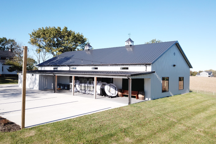 Silo Farms event barn with covered patio area, black metal roof, white steel siding, and rooftop cupolas