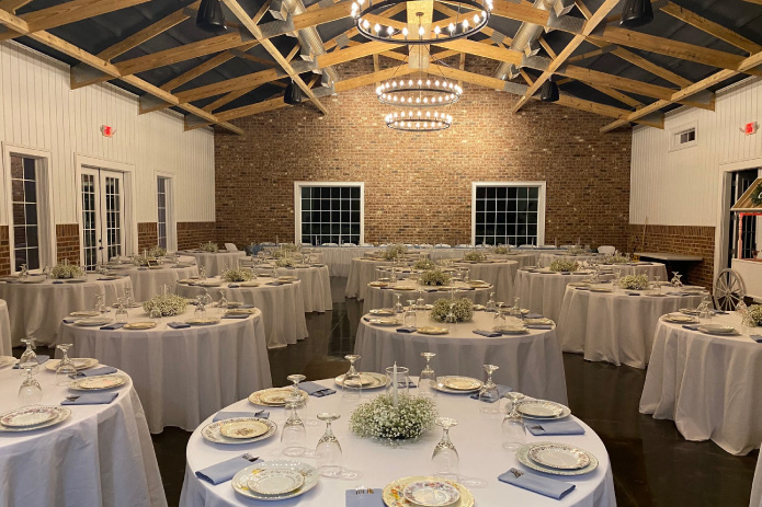 Silo Farms event barn reception space with exposed wood trusses, brick wall, chandeliers, and round banquet tables