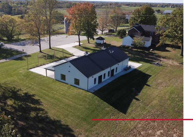 Aerial view of Silo Farms event barn with white siding, black metal roof, and surrounding countryside